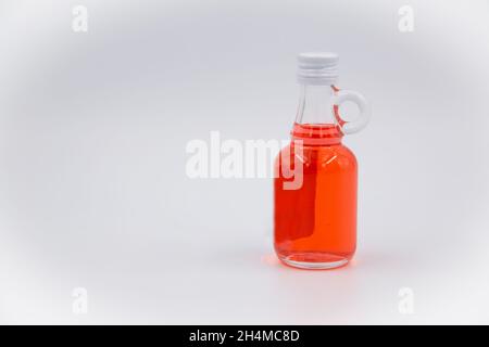 Eine Flasche Saft mit einem Getränk mit roter Johannisbeere und einem grünen Stopfen auf weißem Hintergrund Stockfoto