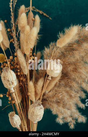 Bouquet von beige getrockneten Blumen auf grün-blauem Hintergrund. Stockfoto