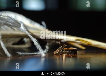 Zwei Eheringe liegen in weißen Federn. Das Konzept der Liebe. Stockfoto