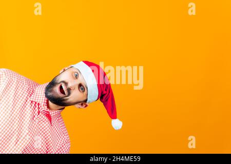 Ein fröhlicher Mann mit einem Bart guck aus dem Rahmen in einem Weihnachtsmannhut hängenden Bubo Stockfoto
