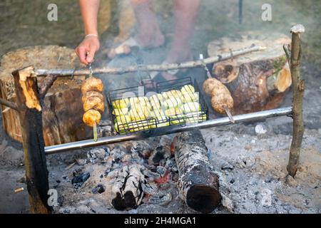 Zucchini und Pilze werden auf einem Feuer im Wald gebraten. Stockfoto