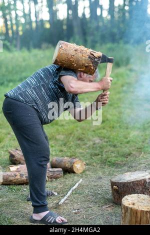 Ein Mann im Wald hackt Holz mit einer Stahlaxt, eine Waldlandschaft mit einem Holzfäller. Stockfoto