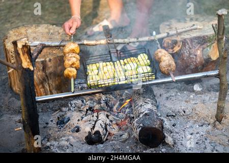 Zucchini und Pilze werden auf einem Feuer im Wald gebraten. Stockfoto