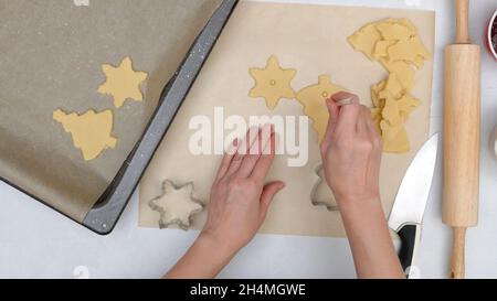 Weihnachts-Shortbread-Kekse mit Himbeermarmelade Rezept, close up Backprozess, flach legen. Koch macht Löcher in der Plätzchenmitte mit einem Stroh Stockfoto