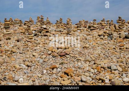 Cairns wurde von Besuchern von Lindisfarne Castle auf Holy Island vor der Küste von Northumberland im Nordosten Englands, Großbritannien, erbaut. Stockfoto