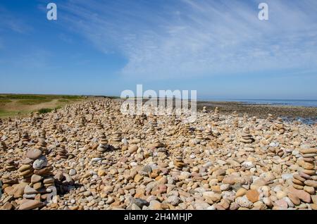 Cairns wurde von Besuchern von Lindisfarne Castle auf Holy Island vor der Küste von Northumberland im Nordosten Englands, Großbritannien, erbaut. Stockfoto