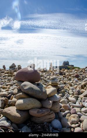 Cairns wurde von Besuchern von Lindisfarne Castle auf Holy Island vor der Küste von Northumberland im Nordosten Englands, Großbritannien, erbaut. Stockfoto
