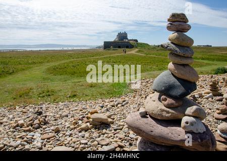 Cairns wurde von Besuchern von Lindisfarne Castle auf Holy Island vor der Küste von Northumberland im Nordosten Englands, Großbritannien, erbaut. Stockfoto