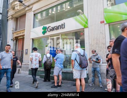 Beyoglu, Istanbul, Türkei - 08.03.2021: Türkische Garanti Bank-Kunden maskieren sich in der Schlange, um gerufen zu werden, weil sie sich vor dem Corona-Virus schützen Stockfoto