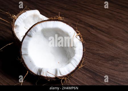 Reife halbgeschnittene Kokosnuss auf einem Holzhintergrund Stockfoto