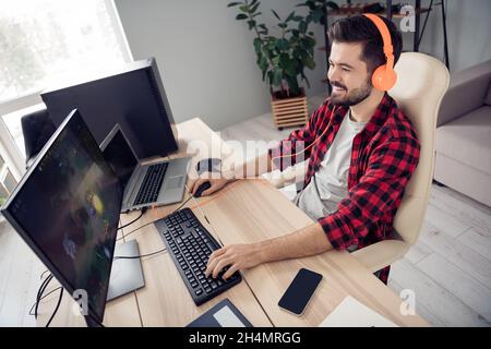 Über Hochwinkel-Profil Seitenansicht der fröhlich fokussierten bärtigen Kerl spielen Videospiel Kampf im Büro Arbeitsplatz Raum innen Stockfoto