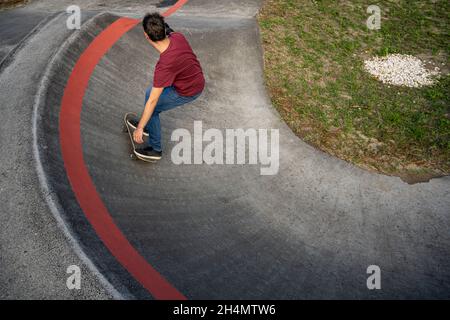 Skateboarder üben an einem sonnigen Tag auf einem Pump Track Park. Stockfoto