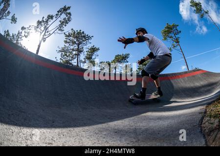 Skateboarder üben an einem sonnigen Tag auf einem Pump Track Park. Stockfoto