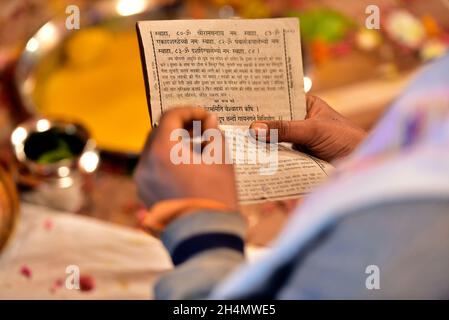 Selektive Fokusaufnahme eines Mannes, der ein religiöses Buch in den Händen auf einem verschwommenen Hintergrund hält Stockfoto