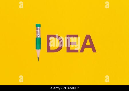 Das Wort 'Idee' auf gelbem Hintergrund. Ansicht von oben oder flach liegend. Stockfoto