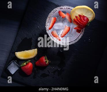 Draufsicht auf ein erfrischendes Getränk mit Erdbeeren und Zitrone auf einer schwarzen Oberfläche Stockfoto