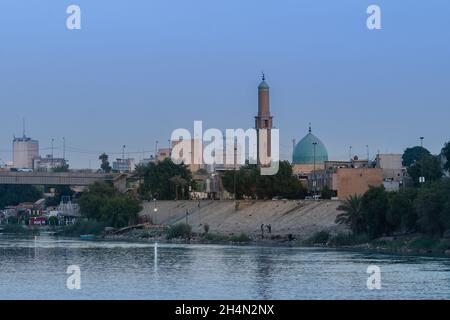 Bagdad, Irak - 11. Oktober 2021: Abendansicht der Al Takarta Moschee mit Blick auf den Tigris Fluss und der Großen Torbrücke im Hintergrund in Ha Stockfoto