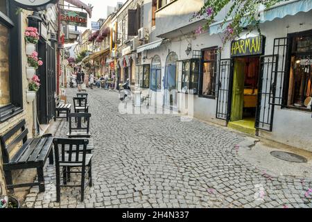 Alacati, Izmir, Türkei – 3. Oktober 2020. Eine schmale gepflasterte Straße in Alacati Resort Stadt der Provinz Izmir in der Türkei. Blick mit Menschen, Stein Hou Stockfoto