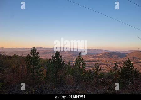 Blauer Himmel der Landschaft von Crni Kamen in Suva Planina Nis. Naturtapete ultra breite Natur mit Stadt in der Ferne, Felder und Bäume aufgenommen Stockfoto