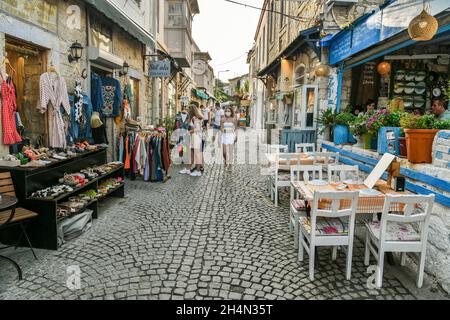 Alacati, Izmir, Türkei – 3. Oktober 2020. Eine schmale gepflasterte Straße in Alacati Resort Stadt der Provinz Izmir in der Türkei. Blick mit Menschen, Stein Hou Stockfoto