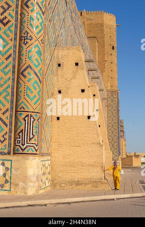 Die Gläubige kommt an der Mauer des Mausoleums von Khoja Ahmed Yasawi (14. Jahrhundert) vorbei und berührt sie. Hauptattraktion für muslime und Touristen in Turkistan Stockfoto