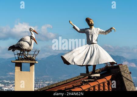 Bursa, Türkei – 10. November 2020. Statue von weißen Störchen und einem wirbelnden Derwisch auf dem Dach eines Gebäudes in der Nähe der Yesil Camii Moschee in Bursa. Stockfoto