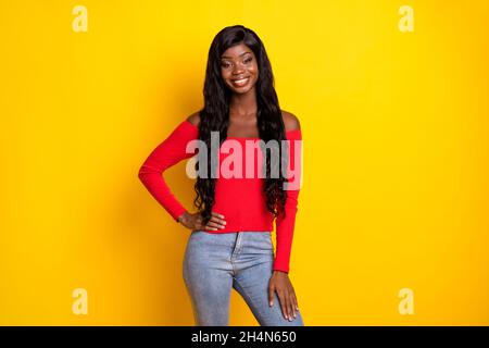 Foto von ziemlich süßen dunklen Haut Mädchen gekleidet roten oberen Arm Taille stehend isoliert gelbe Farbe Hintergrund Stockfoto