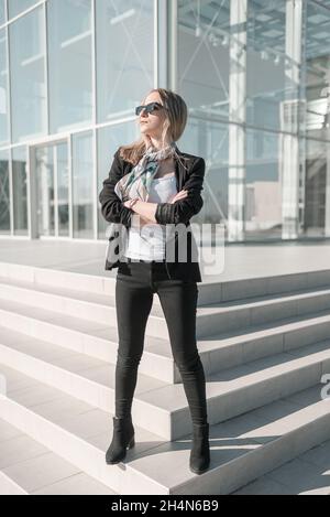 Unabhängige, selbstbewusste junge Geschäftsfrau, die vor dem Bürogebäude steht Stockfoto