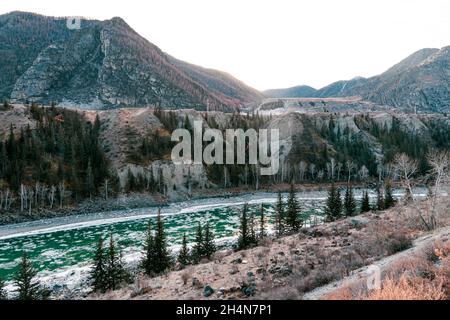 Fluss im Winter. Schöne Winterlandschaft im Winter. Der ungeheizten Gebirgsfluss fließt zwischen Bergen und Pinien. Stockfoto