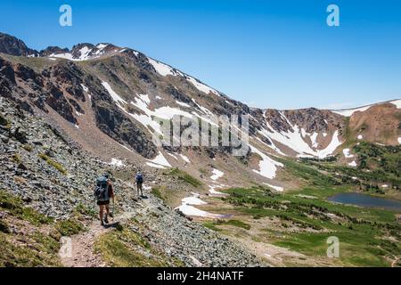 Wanderer mit schweren Packungen und Wanderstöcken im Sommer in schroffem Berggelände, Indian Peaks Wilderness Area, Colorado, USA Stockfoto