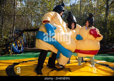 Freunde posieren in aufblasbaren Sumo-Anzügen Stockfoto