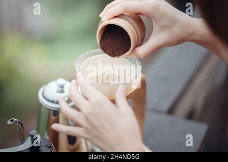 Kaffee von Hand tropfen lassen, Barista gießt den gemahlenen Kaffee in den Filter. Stockfoto