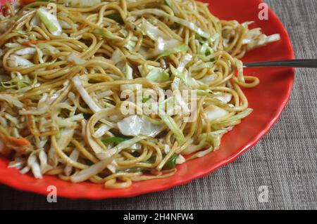 Blick auf Chowmein (Nudeln), serviert in roten Farbteller im Café Stockfoto