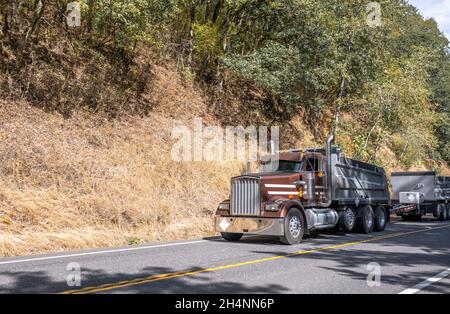 Big Rig Kipper Semi-Truck mit zwei Anhängern transportieren kommerzielle Fracht auf Sattelauflieger läuft für die Lieferung auf dem Umzug auf der Bergstraße mit Stockfoto