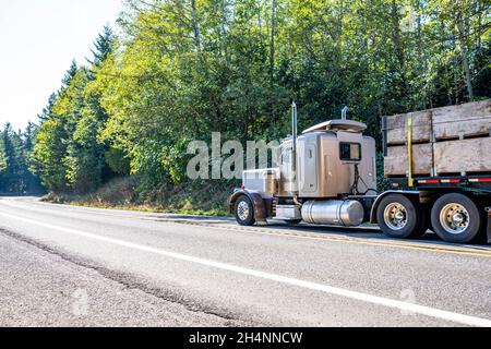 Leistungsstarke beige große Rig klassischen Semi-Truck-Transport durch Schlingen kommerziellen Fracht auf Flachbett Sattelauflieger fahren auf der schmalen Wicklung mountai befestigt Stockfoto