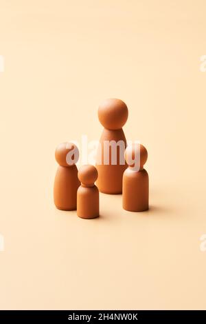 Figuren im minimalistischen Stil einer alleinerziehenden ethnischen Mutter mit Kindern, die verschiedene Familienrealitäten vor beigefarbenem Hintergrund darstellen Stockfoto