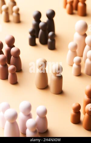 Von oben minimalistischer Stil Holzfiguren von multirassischen Familien umgeben kinderlosen Paar auf beigem Hintergrund Stockfoto