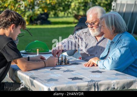 Großeltern und Enkel spielen an einem sonnigen Nachmittag Brettspiele im Freien Stockfoto