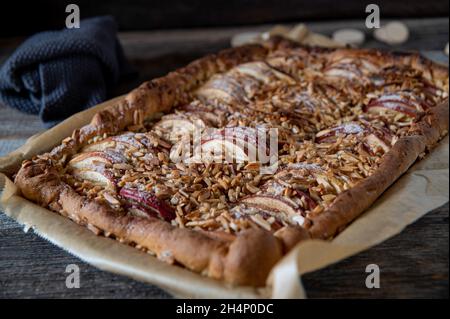 Rustikaler Apfelkuchen oder Apfelkuchen aus Hefeteig und mit Mandeln serviert isoliert auf Holztisch Stockfoto