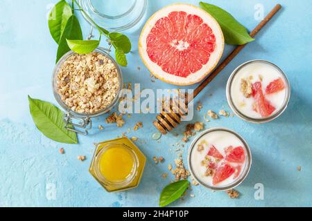Vegan gesundes Frühstück. Müsli mit griechischem Joghurt, Honig und Grapefruit in einem Glas. Draufsicht flach lay Hintergrund. Stockfoto
