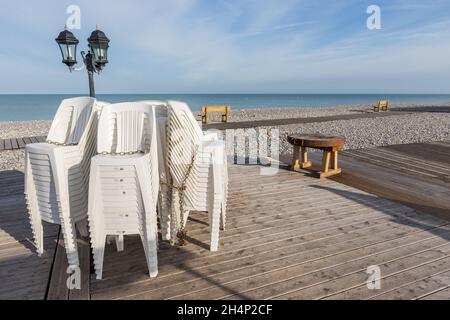 Stühle am Fuß eines Laternenpfades am Rande eines Kiesstrandes in Cayeux-sur-Mer gestapelt. Opal Coast, Frankreich Stockfoto