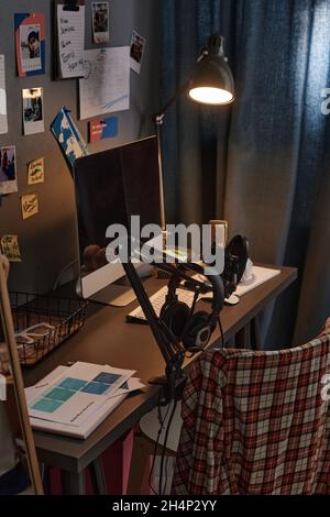 Nahaufnahme des Schreibtisches mit Computermonitor, Lampe und Mikrofon im Schlafzimmer Stockfoto