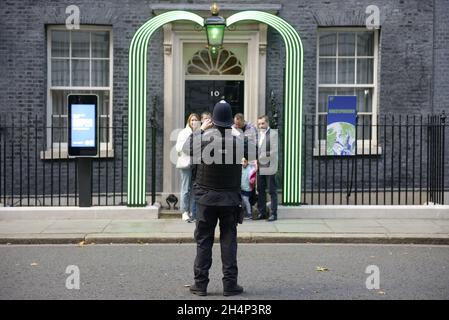 London, England, Großbritannien. Polizeibeamter in der Downing Street fotografiert Besucher vor der Tür von Nummer 10, der Residenz des Premierministers Stockfoto