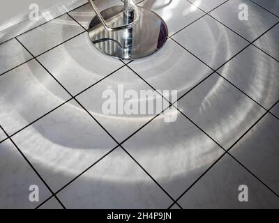 Diese seltsame Lichtshow ist eigentlich Morgensonne, die durch die Wellglas unserer Küchentür spielt und von einem Barhocker auf unsere Fliesen reflektiert wird Stockfoto