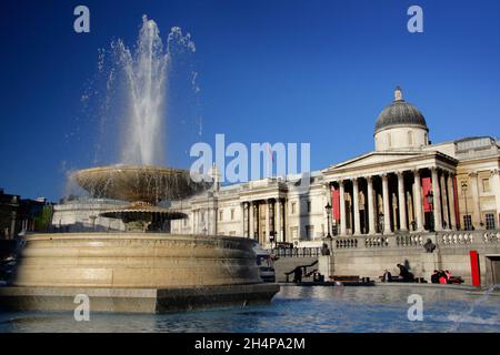 Zwei Lonndon-Wahrzeichen - der Brunnen des Trafalgar Square und die National Gallery. Wir Briten begrüßen eine Gelegenheit - jede Gelegenheit -, eine zu überbieten Stockfoto