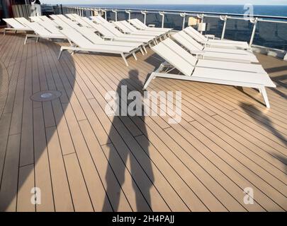 Auf Deck, mein Schatten. Eine der seltsamen Seiten der anhaltenden Pandemie sind Ozeandampfer, die mit Passagieren gefüllt sind und verzweifelt versuchen, von allem zu entfliehen und aro zu segeln Stockfoto