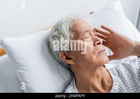 Kranker asiatischer Mann, der auf der Krankenhausstation auf dem Bett liegt Stockfoto