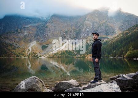 Tourist in der Nähe des Bergsees Morskie Oko in Tatra Nationalpark, Polen. Glücklicher Wanderer auf dem malerischen See in den Bergen im Herbst. Stockfoto