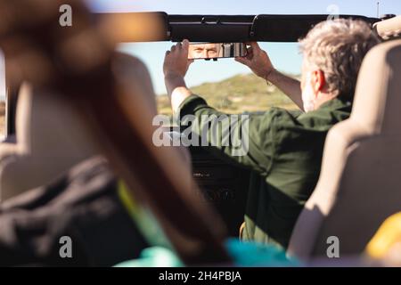 Kaukasischer Mann, der den Rückspiegel im Auto am Meer justiert Stockfoto