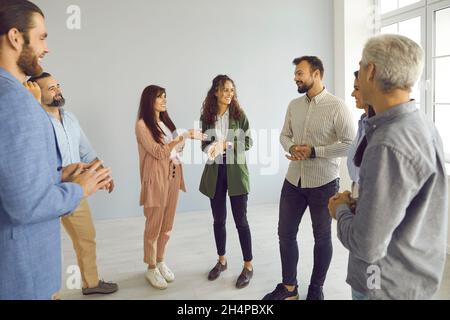 Eine Gruppe junger und reifer Geschäftsleute, die während der Besprechung im Büro stehen und sprechen Stockfoto